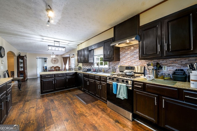 kitchen featuring a textured ceiling, sink, hanging light fixtures, kitchen peninsula, and stainless steel range with gas stovetop