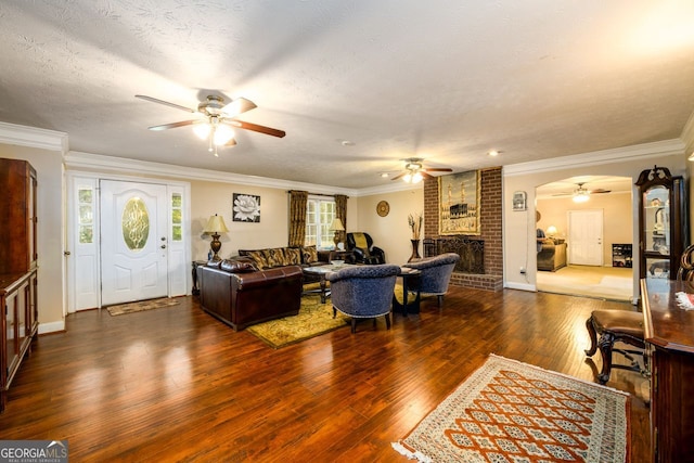 living room with dark wood-type flooring, plenty of natural light, a fireplace, and a textured ceiling