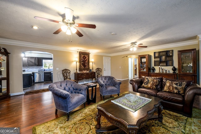 living room with ceiling fan, dark hardwood / wood-style flooring, crown molding, and a textured ceiling