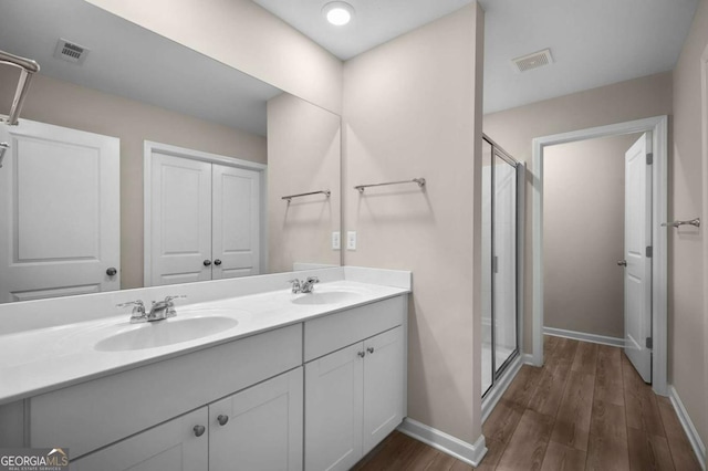 bathroom featuring hardwood / wood-style floors, vanity, and a shower with shower door