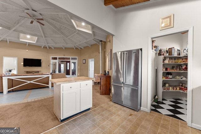 kitchen with white cabinetry, ceiling fan, a towering ceiling, light carpet, and high end fridge