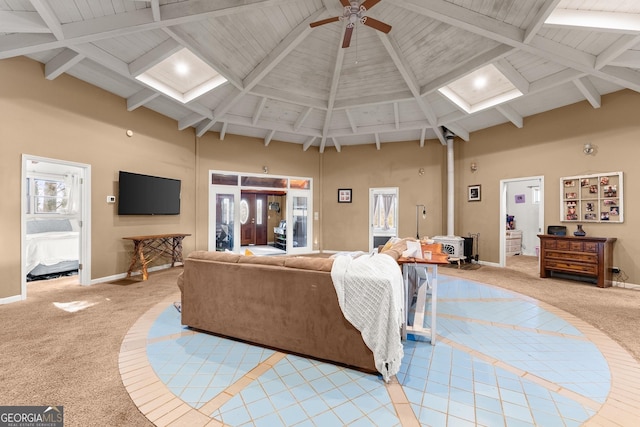 living room with ceiling fan, light colored carpet, a wood stove, and a towering ceiling