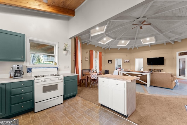 kitchen with ceiling fan, beam ceiling, light colored carpet, and gas range gas stove