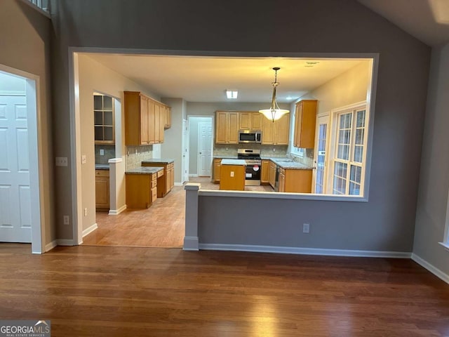 kitchen featuring decorative backsplash, dark hardwood / wood-style flooring, stainless steel appliances, and hanging light fixtures