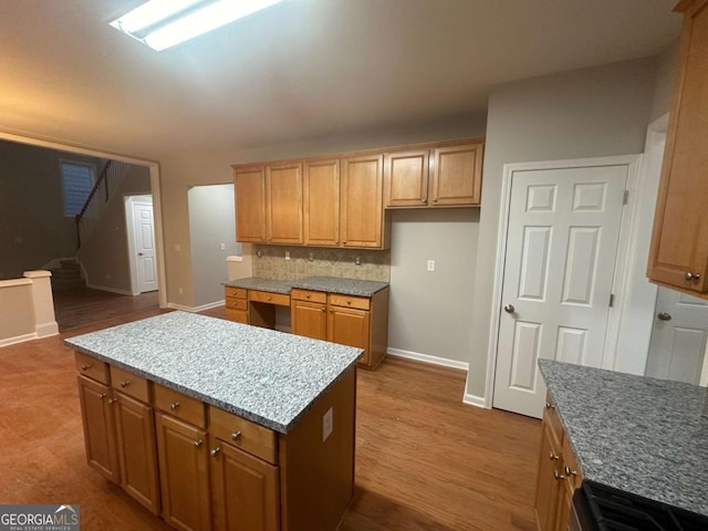 kitchen with hardwood / wood-style floors, a kitchen island, stove, and tasteful backsplash