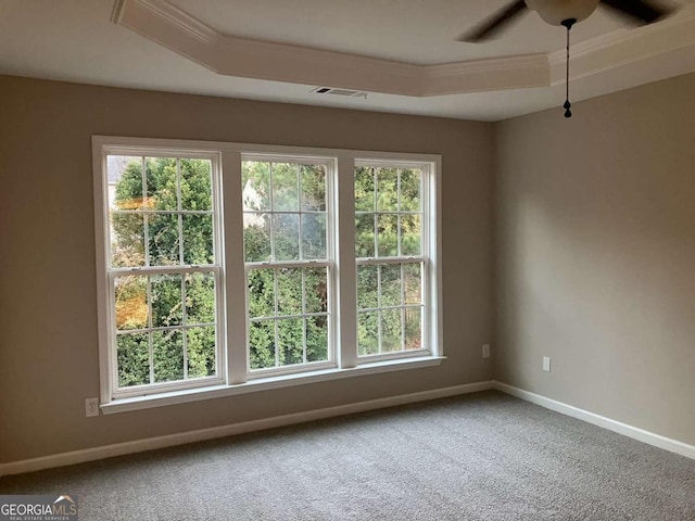 carpeted empty room featuring ceiling fan, crown molding, and a tray ceiling