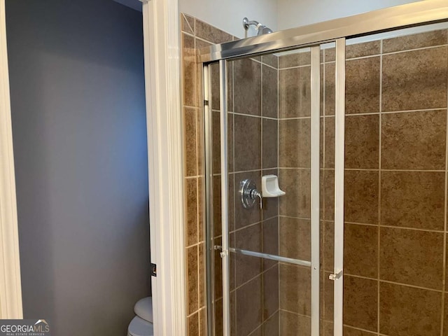 bathroom with toilet and a shower with shower door