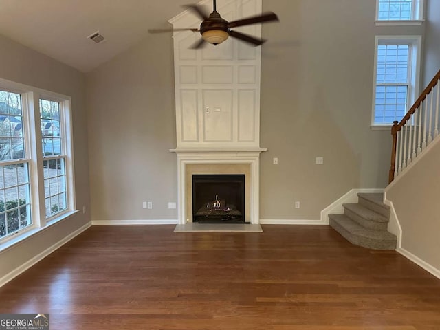 unfurnished living room with lofted ceiling, ceiling fan, a large fireplace, and plenty of natural light