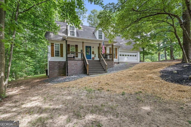 cape cod house featuring covered porch and a garage