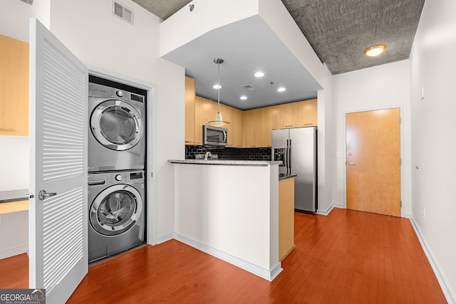 laundry area featuring stacked washer / dryer and light hardwood / wood-style floors