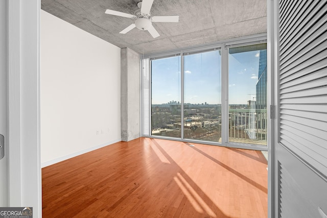 unfurnished room featuring hardwood / wood-style flooring, ceiling fan, expansive windows, and a wealth of natural light