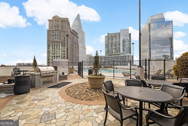 view of patio with a grill, a community pool, and exterior kitchen