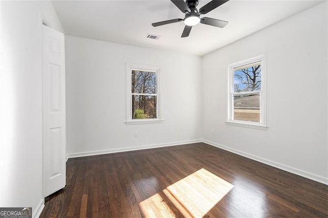 spare room with dark hardwood / wood-style flooring, a wealth of natural light, and ceiling fan