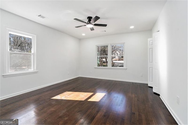 empty room with ceiling fan, a healthy amount of sunlight, and dark hardwood / wood-style floors