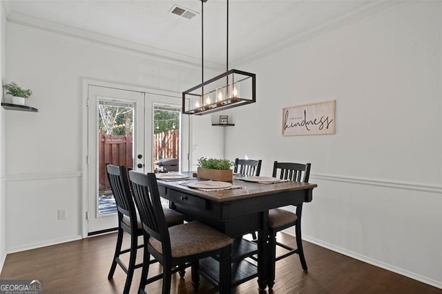 dining area featuring dark hardwood / wood-style floors, crown molding, and french doors