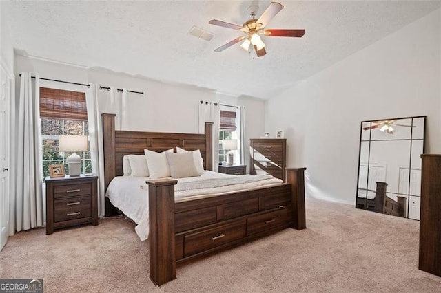 bedroom with ceiling fan, light colored carpet, and a textured ceiling