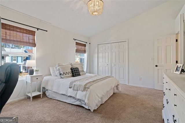 carpeted bedroom featuring multiple windows, vaulted ceiling, and a closet