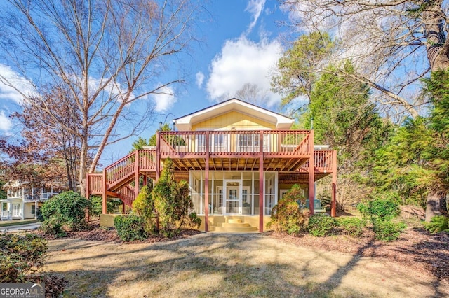 rear view of property with stairway, a deck, and a sunroom