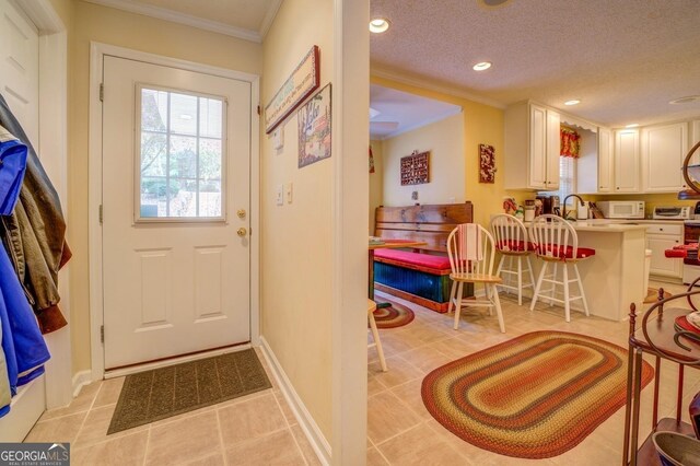 doorway with a textured ceiling, ornamental molding, and sink