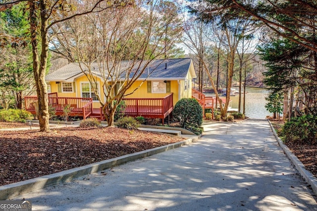 view of front facade with driveway, a shingled roof, and a water view