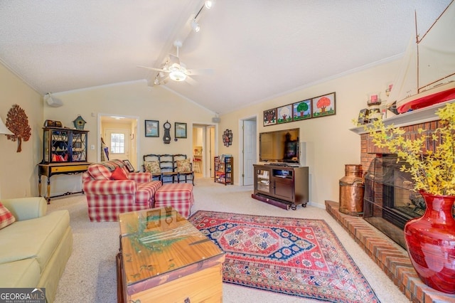 living room featuring a ceiling fan, track lighting, carpet floors, a fireplace, and lofted ceiling