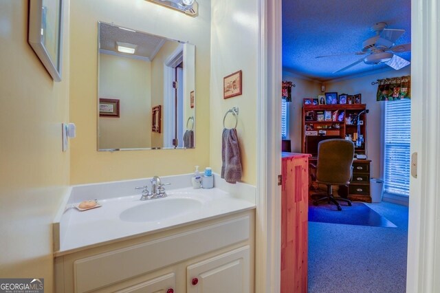 bathroom with ceiling fan, ornamental molding, a textured ceiling, and vanity