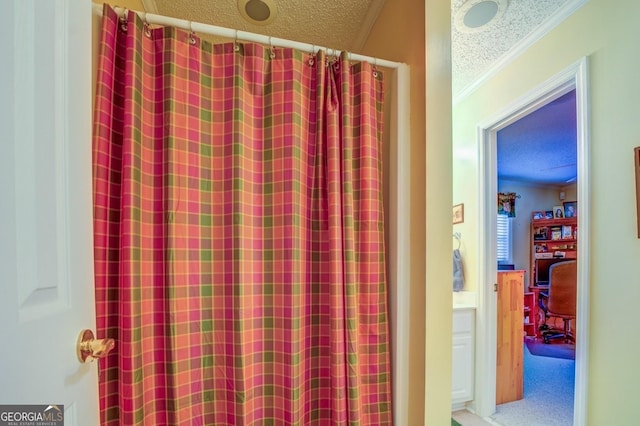 bathroom featuring a textured ceiling, ornamental molding, and a shower with curtain