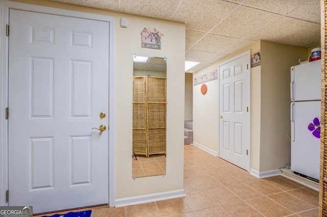 exterior space featuring a paneled ceiling, baseboards, and light tile patterned floors
