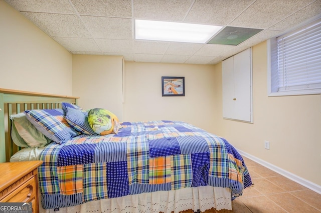 tiled bedroom with a drop ceiling and baseboards