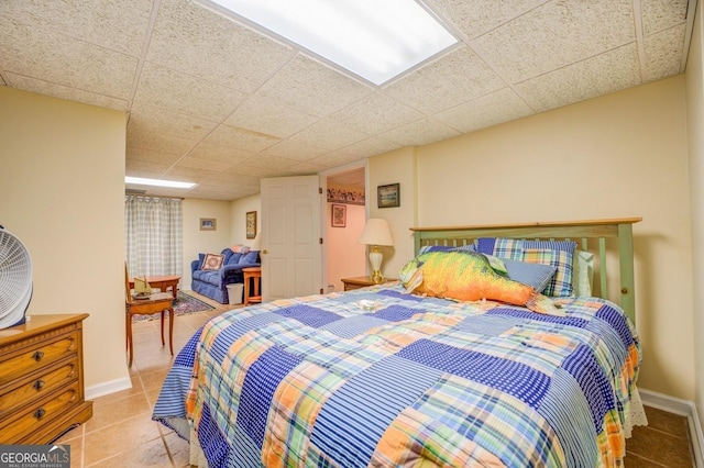 tiled bedroom with a paneled ceiling and baseboards