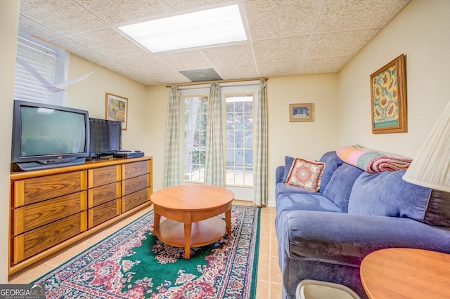 living area featuring light tile patterned flooring and a paneled ceiling