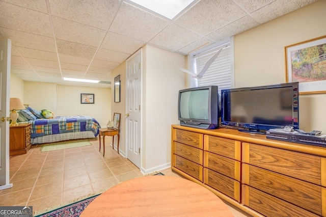 bedroom featuring a drop ceiling, baseboards, and light tile patterned floors