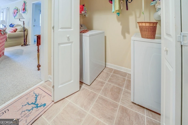 washroom featuring separate washer and dryer, light tile patterned flooring, light colored carpet, baseboards, and laundry area