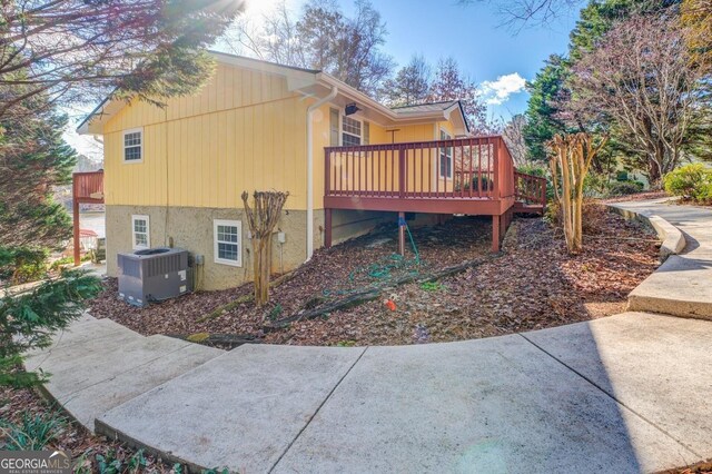 view of side of home with central AC unit and a wooden deck