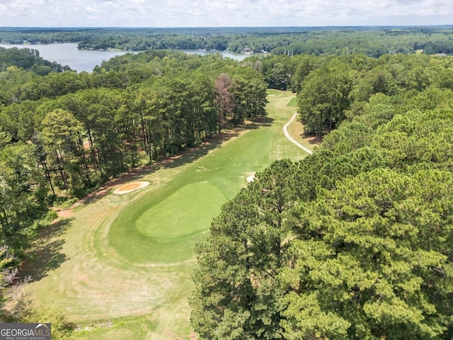 drone / aerial view with view of golf course, a wooded view, and a water view