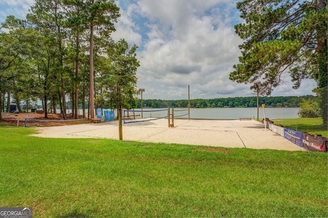surrounding community with volleyball court, a lawn, and a water view