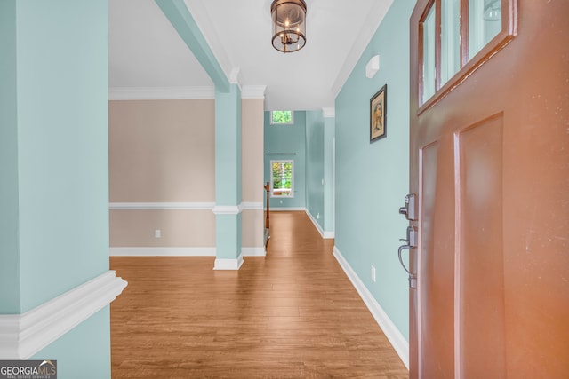 foyer with light hardwood / wood-style flooring, ornamental molding, and a notable chandelier