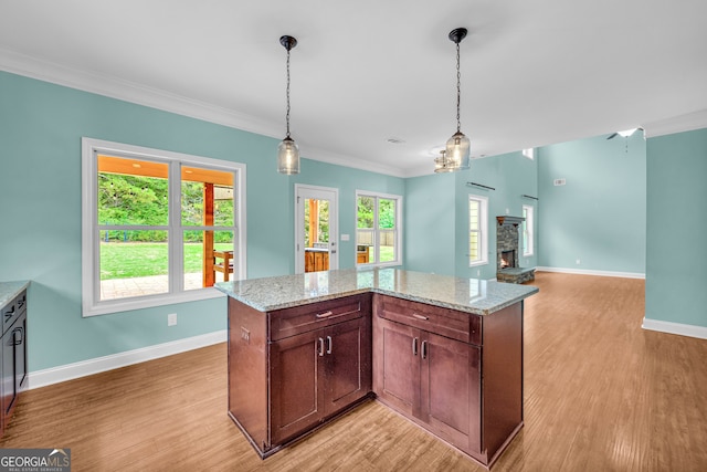 kitchen featuring light stone countertops, ornamental molding, hanging light fixtures, and light hardwood / wood-style floors