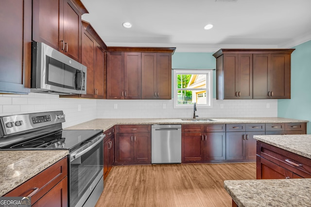 kitchen featuring crown molding, sink, stainless steel appliances, and light hardwood / wood-style flooring