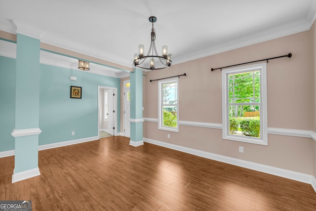 spare room with a chandelier, hardwood / wood-style flooring, crown molding, and a healthy amount of sunlight