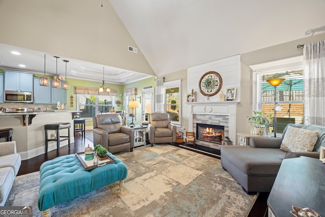 living room featuring a fireplace, high vaulted ceiling, dark wood-type flooring, and a notable chandelier