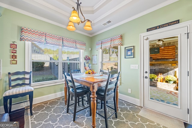 dining room featuring a raised ceiling, crown molding, and a notable chandelier