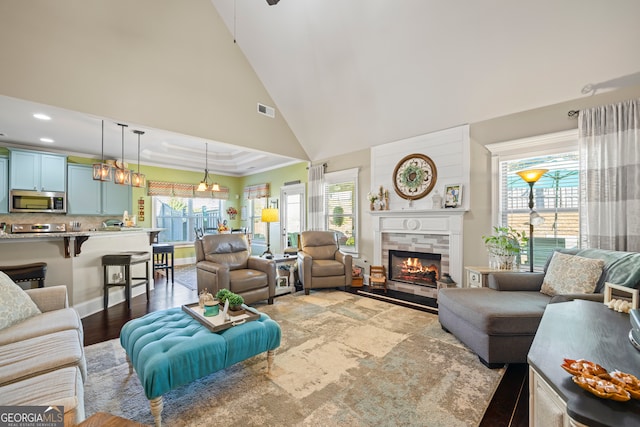 living room featuring a tile fireplace, wood-type flooring, and high vaulted ceiling