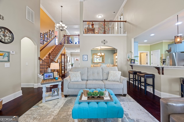 living room with a notable chandelier, ornamental molding, and dark wood-type flooring