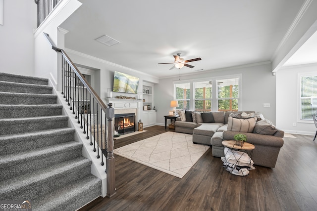 living room with built in shelves, ceiling fan, ornamental molding, and wood-type flooring