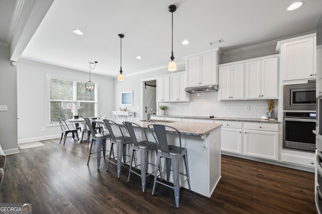 kitchen with decorative light fixtures, white cabinetry, a kitchen island with sink, and appliances with stainless steel finishes