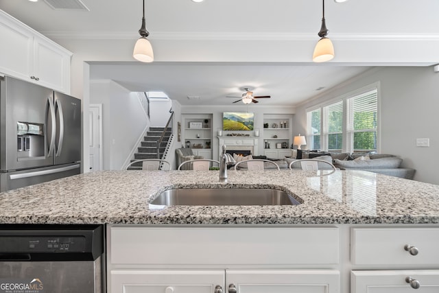 kitchen with pendant lighting, light stone countertops, sink, and appliances with stainless steel finishes