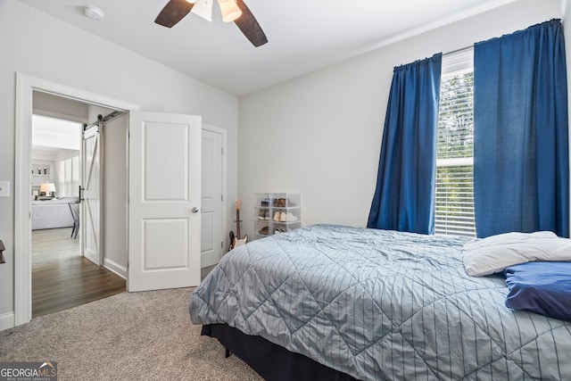 bedroom featuring carpet floors, ceiling fan, and a barn door