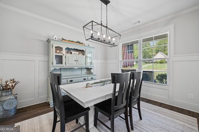 dining space featuring crown molding, wood-type flooring, and an inviting chandelier