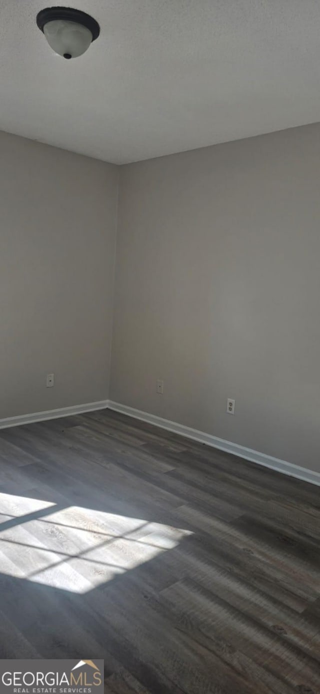 unfurnished room with dark hardwood / wood-style flooring